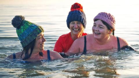 Family having a moment together messing about while winter sea swimming 