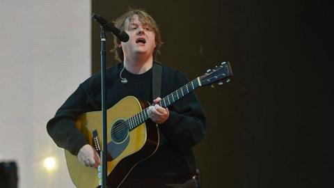 Lewis Capaldi performs onstage with an acoustic guitar