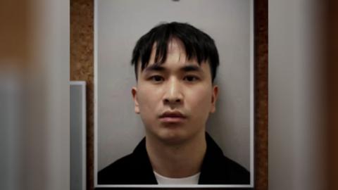 A mugshot of a man, Zhenhao Zou, on a pin board