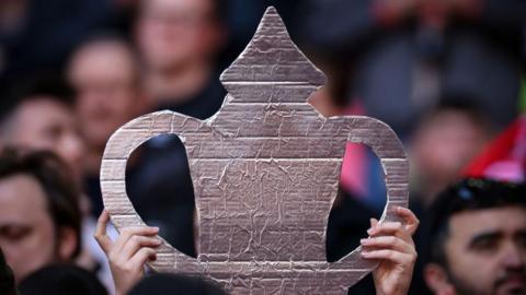 A fan holds a tin foil FA Cup trophy