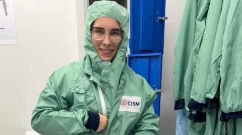 Kateryna mewn dillad amddiffynnol gwyrdd golau sydd hefyd yn gorchuddio'i gwallt