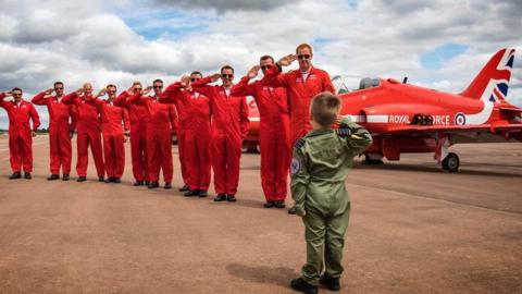 Little boy and Red Arrows crew saluting each other