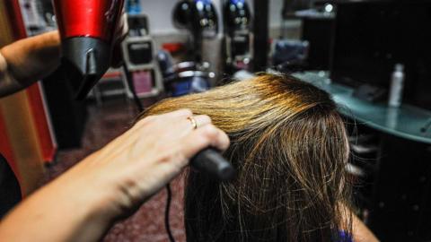 A dark-haired woman is getting a hair cut