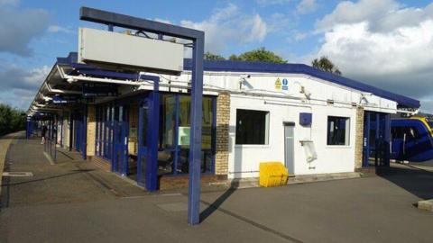 The empty platform at Rochdale station which is a white building with blue platforms