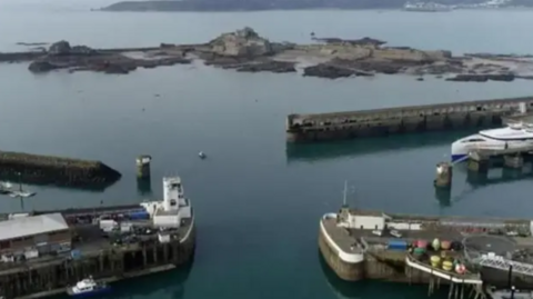 An elevated view of St Helier Harbour showing quaysides and boats. The water is calm.