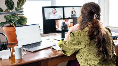 A young woman working from home. On her screen are three other people, as if she's in a zoom call