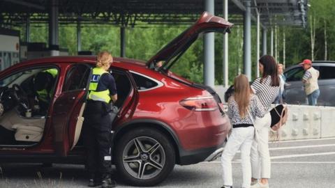 A customs officer checks a Russian car at the border with Finland in July