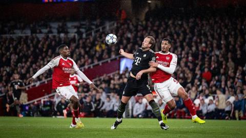 Harry Kane brings down the ball under pressure from William Saliba