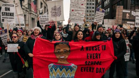 A group of teachers on strike march with protest signs