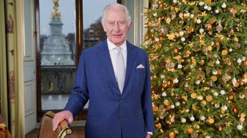 King Charles next to a Christmas tree