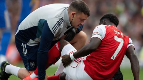 Bukayo Saka receives treatment on the pitch during Arsenal v Leeds