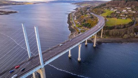 An aerial view of the Kessock Bridge, Beauly Firth and an area of headland with the village of North Kessock along its shoreline.