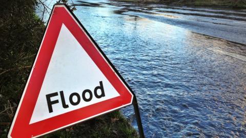 Flood sign by the side of a flooded road