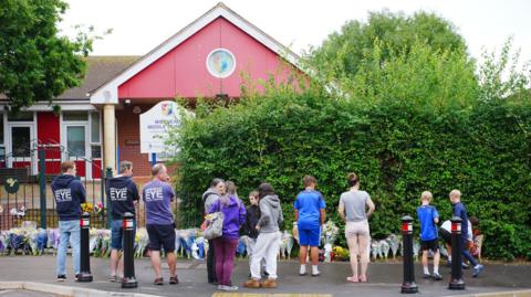 People gather to lay flowers outside school 