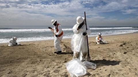 Crews pick the tar from the beach after an oil spill off the coast of Huntington Beach, California, USA, on 4 October 2021