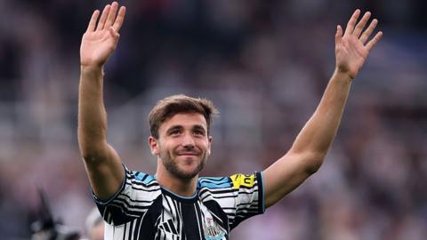 Nico Gonzalez waving to Newcastle fans wearing a Newcastle kit