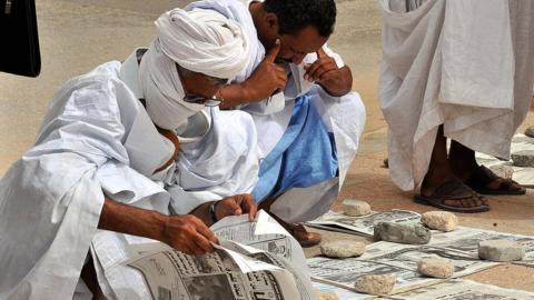 Mauritanians read newspapers on a main street in Nouakchott