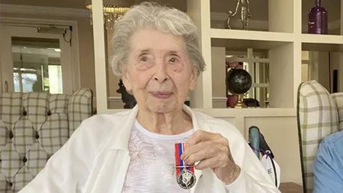 Older woman holding shiny military medal