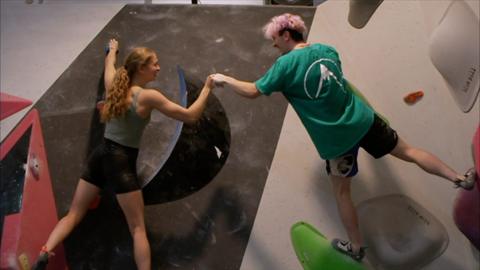 Two climbers fist-bumping on climbing wall