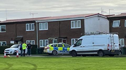 The outside of a property off Ostend Road in Walcott. There is a police car parked outside and a police officer is stood within the shot.