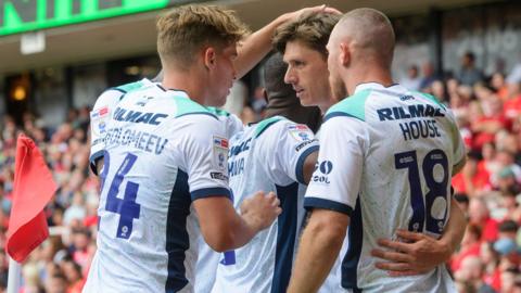 Lincoln City players, wearing their white away shirt, celebrate Adam Reach's goal against Middlesbrough