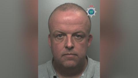 A police mugshot of a bald man wearing a grey top. The Staffordshire Police badge is visible in the top right.