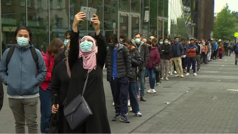 Woman taking photo on phone in front of queue