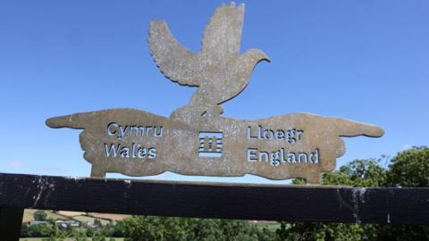 A sign pointing in the direction of Wales and England