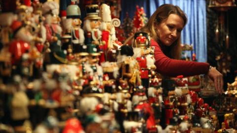 A stall holder arranges her display of Christmas decorations at Birmingham's Frankfurt Christmas market