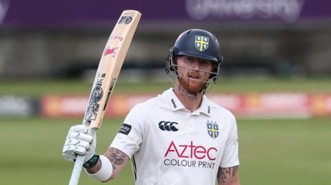 Ben Stokes raises his bat with his right hand after scoring a 50