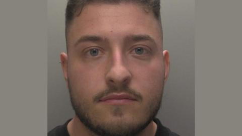 Police mugshot of Luke Greenfield with a moustache 