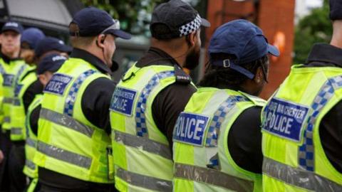 A row of officers from Greater Manchester Police wearing yellow hi vis jackets and caps during the unrest in the city