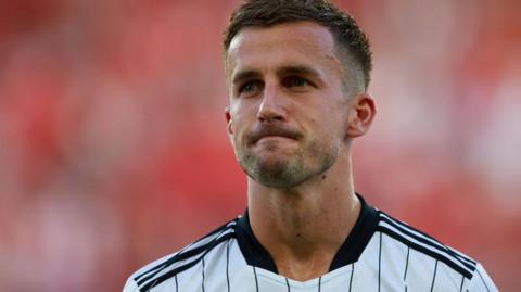 Joe Bryan looks on wearing a Fulham shirt, which is white with black pinstripes.