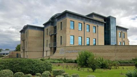 Anglo American's Resolution House offices. A large modern brick building behind a brick wall bearing an Anglo American sign.