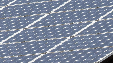 Rows of blue and white solar panels on a sloping structure. 