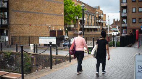 Two women walk side by side near in Manchester city centre