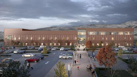 This is a generated image of what the new hospital building would look like. In the foreground there is a car park that has been laid out with a few trees. The building itself is long and three storeys high. The colour is a little like sandstone, which is a common building material in the HIghlands. Mountains can be seen in the background.