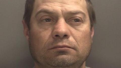 A man with dark hair, whose head is at the top and bottom of the image.