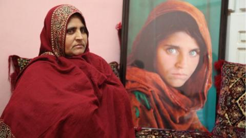 Sharbat Gula sits alongside the iconic image taken when she was a child refugee