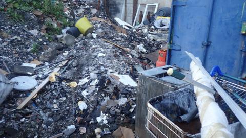 A huge pile of rubbish including ash, buckets and a shopping trolley