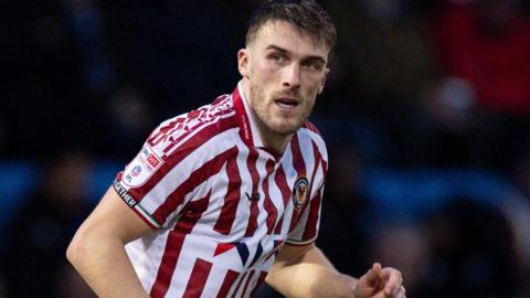 Ryan Delaney in action for Newport County in a red and white striped shirt