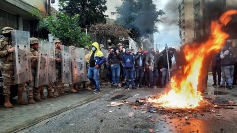 Security forces stand guard as demonstrators set fire near a politician's house in Tripoli, Lebanon. Photo: 28 January 2021