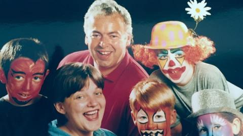 Paul and Lauren Staton pictured in the middle of four children who have their faces painted in bright colours.