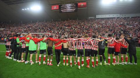 The Sunderland squad line up arms around each other's shoulders in front of fans at the Stadium of Light celebrating the Championship play-off semi-final win against Coventry.