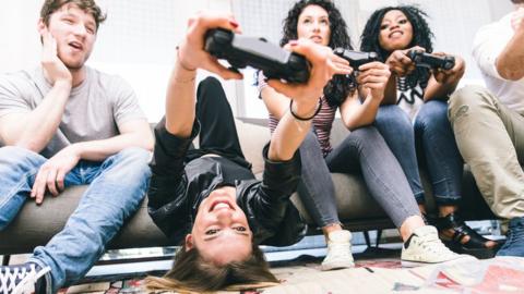 Young people playing video games on sofa