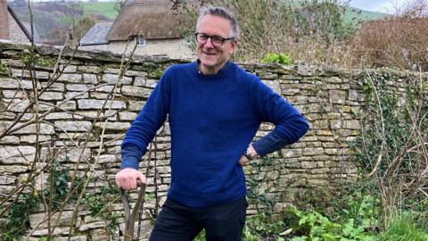 Michael Mosley in the garden holding a shovel