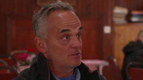 Simon Gleave, chairman of Adlington Parish Council, has short grey hair. He is wearing a dark jacket over a blue top.