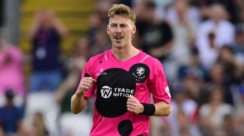 Riley Meredith clenches his fists in celebration while on the pitch during a Somerset match