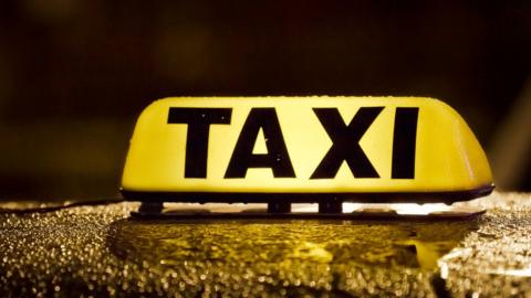 An illuminated taxi sign on top of a cab