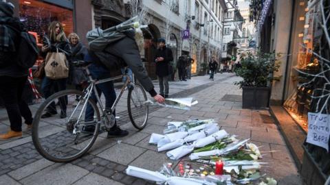 A man on bicycle lays flowers on the street in tribute to the victims of the deadly shooting in central Strasbourg on 12 December, 2018